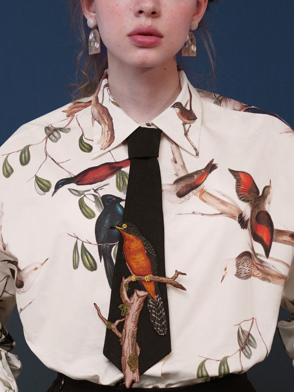 Embroidered tie of a small bird playing on a branch